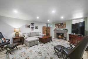 Living room featuring a stone fireplace, recessed lighting, wood finished floors, and plenty of natural light