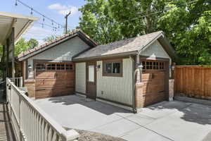 View of front of home featuring a garage, an outbuilding, and a shingled roof