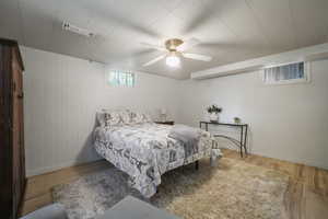 Bedroom with wood finished floors, baseboards, a ceiling fan, and wood walls