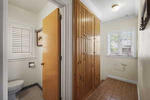 Bathroom with toilet, ornamental molding, tile patterned flooring, and baseboards
