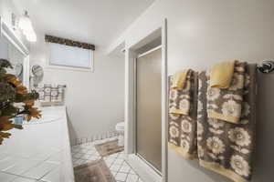 Full bathroom with a stall shower, vanity, tile patterned flooring, and toilet