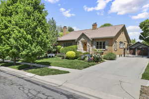 English style home with driveway, a front yard, a chimney, brick siding, and stone siding