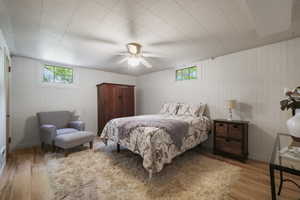 Bedroom with wood finished floors, a ceiling fan, and wood walls