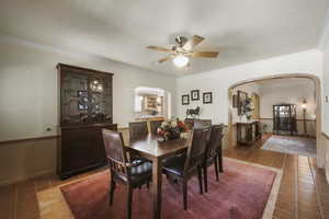 Dining area featuring arched walkways, tile patterned flooring, a ceiling fan, crown molding, and baseboards