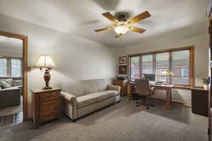 Carpeted home office with plenty of natural light and ceiling fan