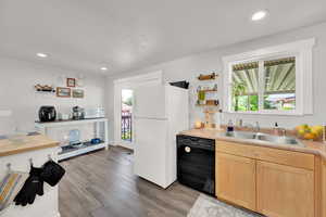 Kitchen with white appliances, a sink, light brown cabinetry, light wood finished floors, and light countertops