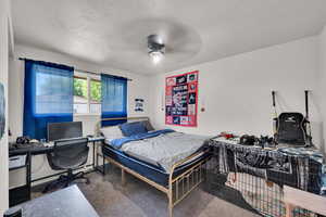 Carpeted bedroom with an office area and a ceiling fan