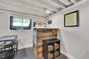 Interior space with baseboards, concrete floors, and beamed ceiling