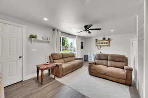 Living area featuring wood finished floors, a ceiling fan, recessed lighting, and baseboards