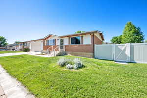 View of front of house featuring brick siding, a gate, driveway, and an attached garage