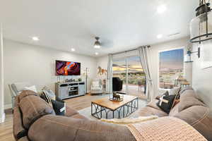 Living room with light wood-style flooring, a ceiling fan, recessed lighting, and baseboards