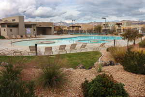 Community pool featuring a hot tub, a residential view, a patio area, and a mountain view