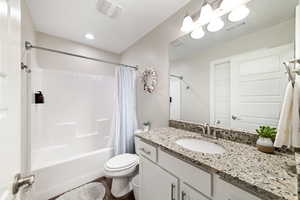 Bathroom featuring shower / bathtub combination with curtain, toilet, vanity, and wood finished floors
