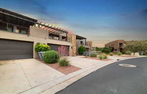 Contemporary house featuring stucco siding, concrete driveway, an attached garage, and a balcony