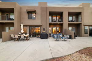 Rear view of property featuring stucco siding, a balcony, a patio area, and outdoor dining area