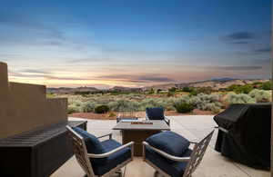 Patio terrace at dusk with a patio, a mountain view, a grill, and a fire pit