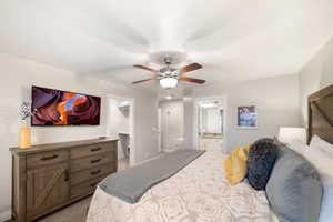 Carpeted bedroom with a spacious closet, ensuite bathroom, baseboards, and ceiling fan