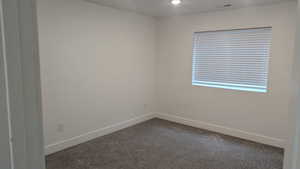 Unfurnished room featuring dark carpet and baseboards