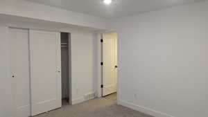 Unfurnished bedroom with light colored carpet, baseboards, and a closet