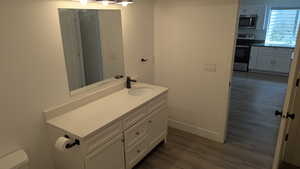 Bathroom featuring vanity, wood finished floors, toilet, and baseboards