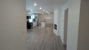Kitchen featuring stainless steel appliances, white cabinets, a sink, light wood finished floors, and baseboards