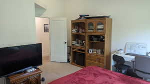 Bedroom featuring light colored carpet and a desk