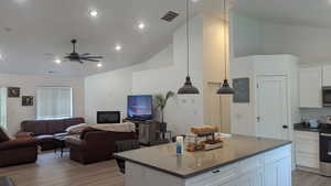 Kitchen featuring stainless steel appliances, light wood-type flooring, open floor plan, a ceiling fan, and white cabinetry