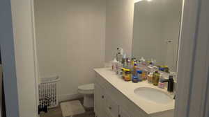 Bathroom with toilet, vanity, wood finished floors, and baseboards