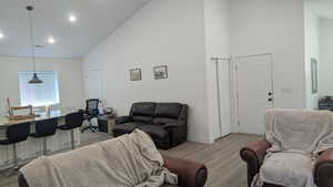 Living room featuring high vaulted ceiling, light wood finished floors, baseboards, and recessed lighting