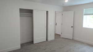 Unfurnished bedroom featuring carpet flooring, baseboards, and a closet
