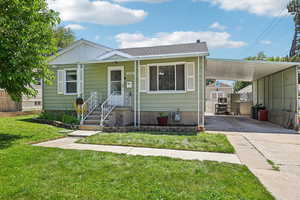 View of front of house featuring driveway, a carport, and a front lawn