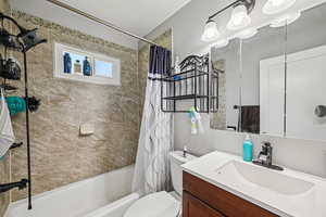 Full bath with shower / tub combo with curtain, vanity, and toilet