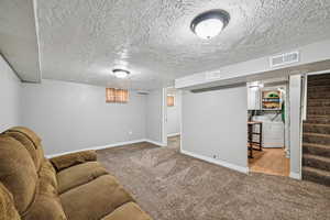 Living area featuring washer and dryer, carpet flooring, stairway, and baseboards