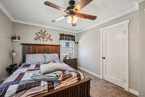 Bedroom featuring carpet, crown molding, baseboards, and ceiling fan