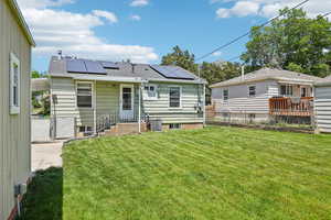 Back of house with roof mounted solar panels, central AC unit, and roof