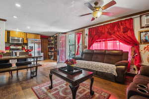Living area featuring healthy amount of natural light, recessed lighting, ceiling fan, crown molding, and wood finished floors