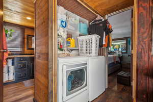 Laundry room featuring washer and dryer, wood ceiling, and wood finished floors