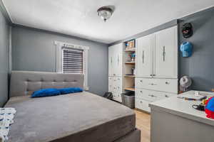 Bedroom with light wood-style floors and crown molding