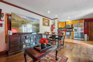 Living room with ornamental molding, recessed lighting, and wood finished floors