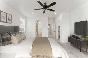 Bedroom featuring arched walkways, light carpet, recessed lighting, ceiling fan, and baseboards