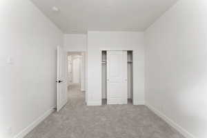 3rd bedroom featuring light colored carpet, baseboards, a closet, and arched walkways