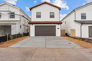 Spanish Mission Exterior home featuring a tiled roof, an attached 2 car garage, stucco siding, and concrete driveway