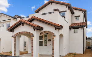 View of front of home featuring a tiled roof, central AC unit, and stucco siding