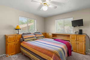 Bedroom with light carpet, a textured ceiling, ceiling fan, and baseboards