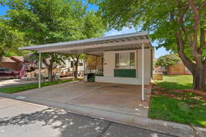 View of front of house with an attached carport and a front lawn