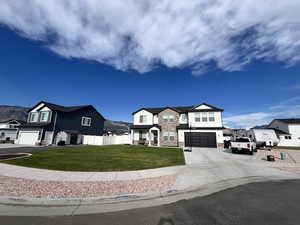 View of front of home featuring an attached garage, stone siding, concrete driveway, and a residential view