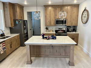 Kitchen featuring stainless steel appliances, a sink, light wood finished floors, decorative light fixtures, and recessed lighting