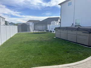 View of yard with a trampoline, a swimming pool, and a residential view
