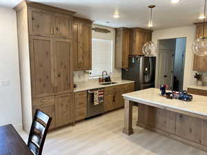 Kitchen featuring stainless steel appliances, a sink, light countertops, pendant lighting, and recessed lighting