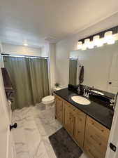 Bathroom with marble finish flooring, vanity, toilet, a shower with curtain, and a textured ceiling